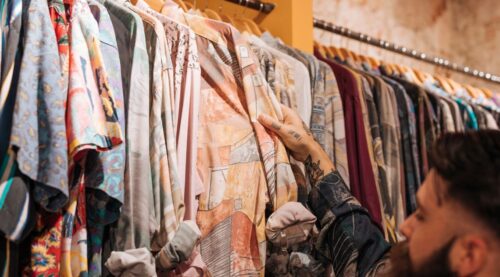 A person looking through a rail of second-hand luxury clothing